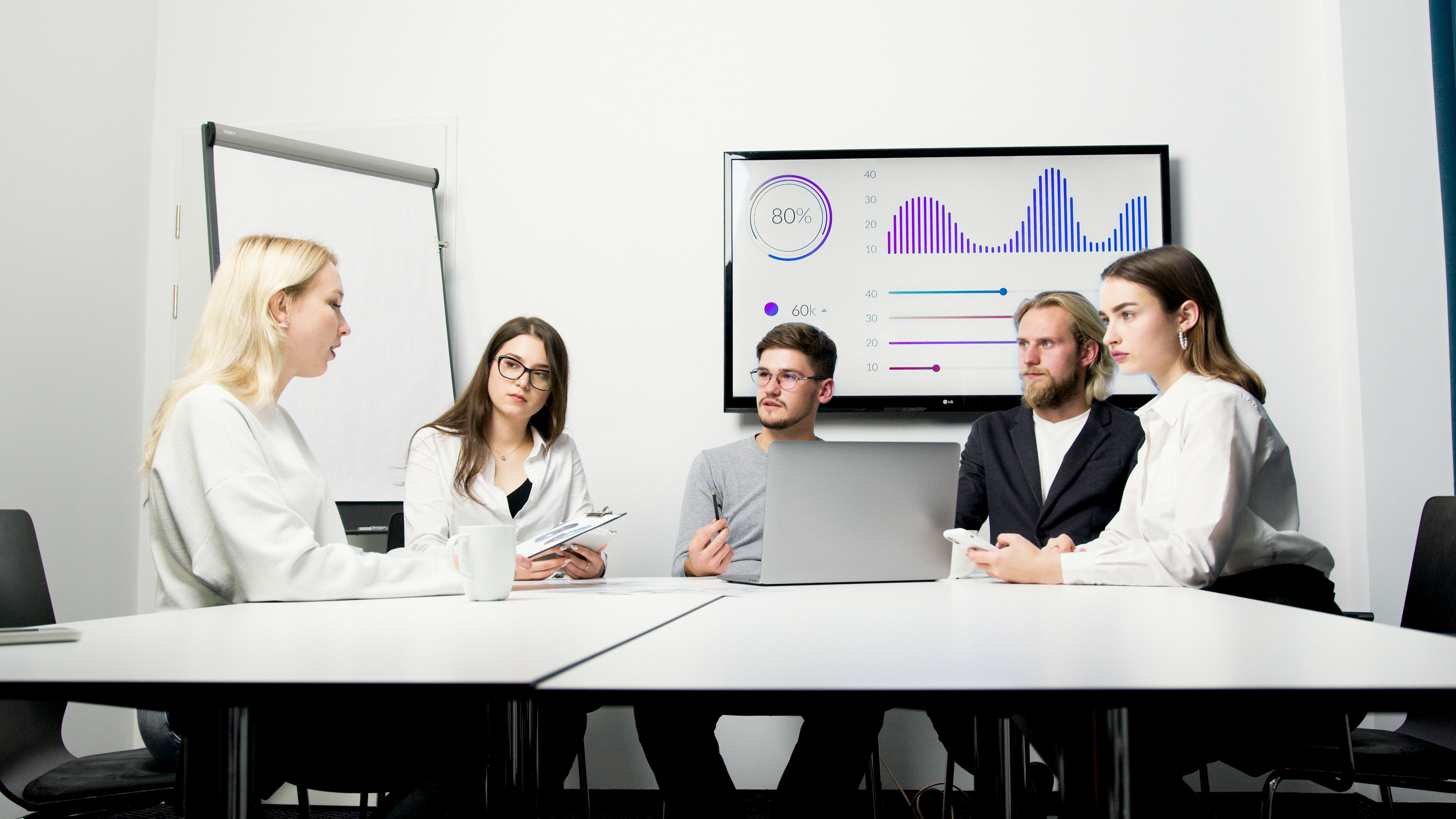 A group of professionals engaged in a business meeting with data presentation.