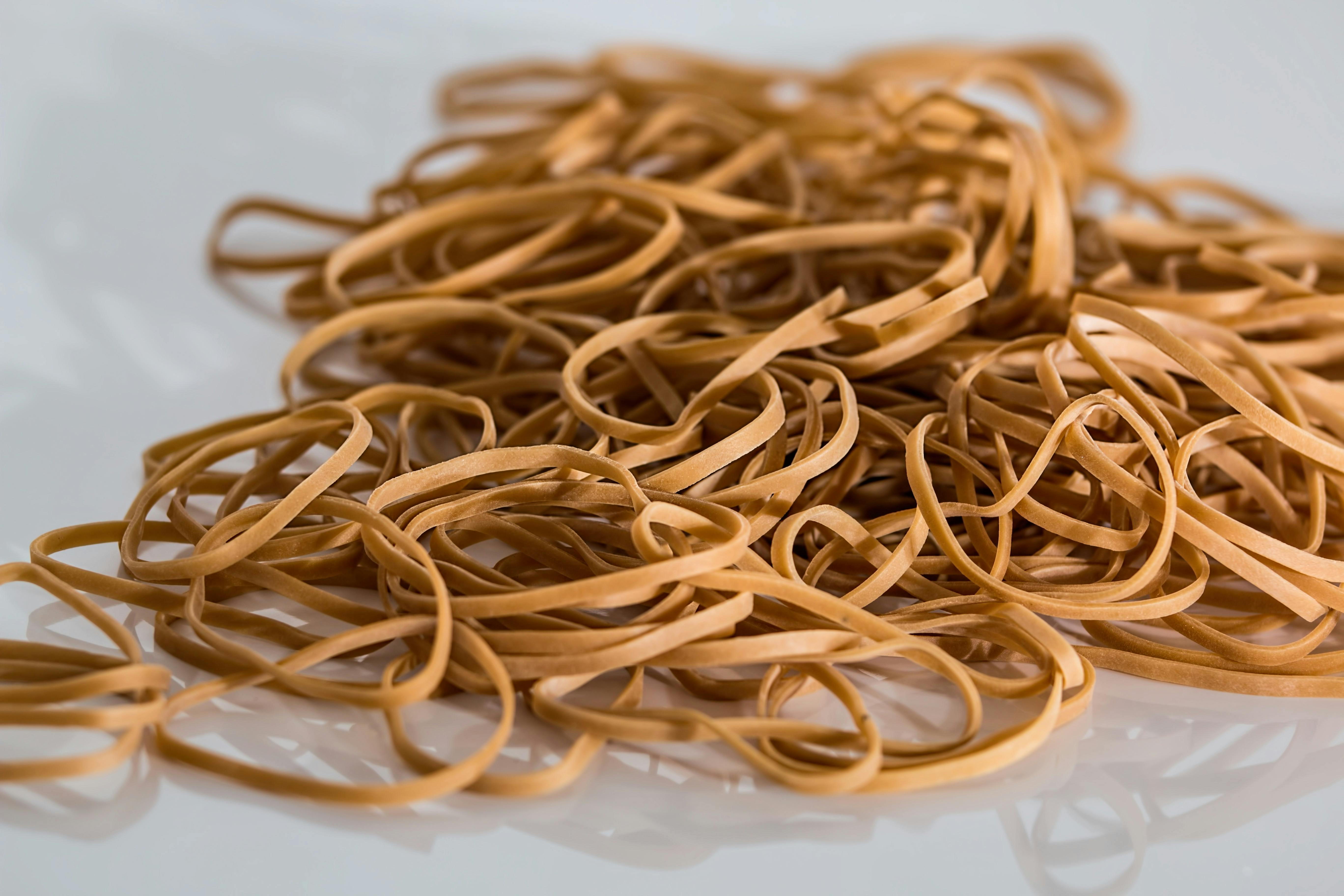 A close-up image of a scattered pile of brown rubber bands on a reflective surface.